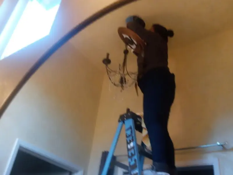 Electrician installing a chandelier in a Blanding residence